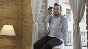 Man in casual clothes using phone and having video call