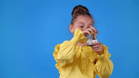 4k slow motion video of one young girl playing with a toy and smiling over blue background.