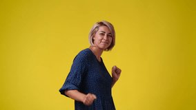 4k video of one woman who dancing on yellow background.