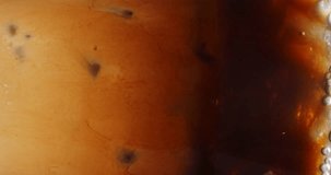 4K footage vertical video front view SLO MO CU, Cappuccino iced coffee mug where milk is being mixed with coffee, coffee art concept.