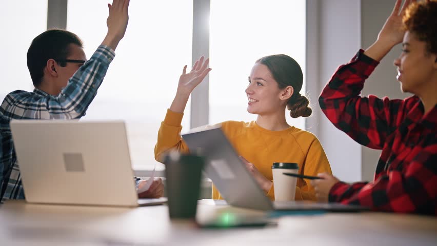 Successful teamwork. Colleagues sitting at table in office, smiling happy and laugh, giving each other five. Gesture great job. Office workers completed important task or business, celebrate victory. Royalty-Free Stock Footage #1100439201
