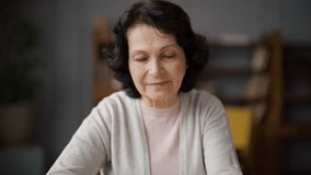 Adult woman, grandmother or mother calls her children or grandchildren, toothy smile. Happy telephone conversation with loved ones, close relatives. Pick up phone or dial number. Home cozy interior. - Powered by Shutterstock - Get 15% off with code: PIKWIZARD15