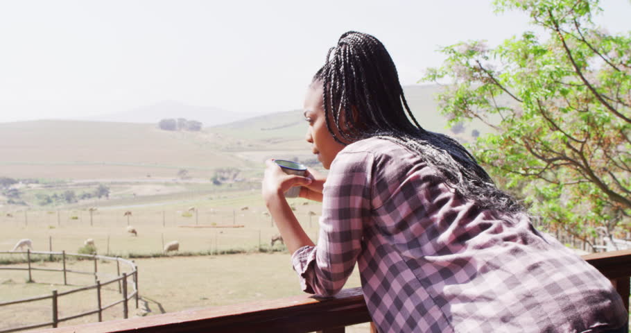 Thoughtful african american woman drinking coffee in log cabin, slow motion. Lifestyle, domestic life, countryside and nature concept.