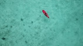 Aerial view of woman with red surfboard in tropical water. High quality 4k footage