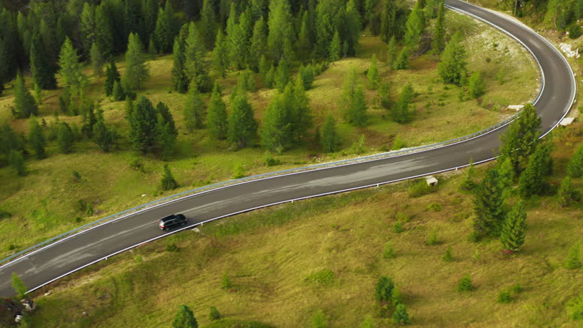 Car drives on curvy asphalt road winding along large forest with evergreen coniferous trees. Serpentine freeway across forestry mountains aerial view Royalty-Free Stock Footage #1100445261