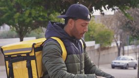 Food delivery concept. Young black man driver with backpack putting helmet on in the city to deliver products for customers who order online purchases. Black male happy with his job. - Powered by Shutterstock - Get 15% off with code: PIKWIZARD15