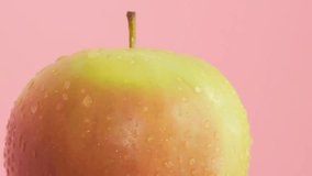 Macro video of a green apple with water drops isolated on a yellow background. Fresh fruit concept