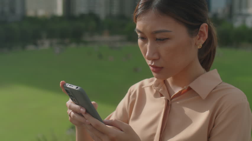 Tilt down low angle shot of beautiful Asian woman standing outdoor in city and using mobile phone | Shutterstock HD Video #1100453029