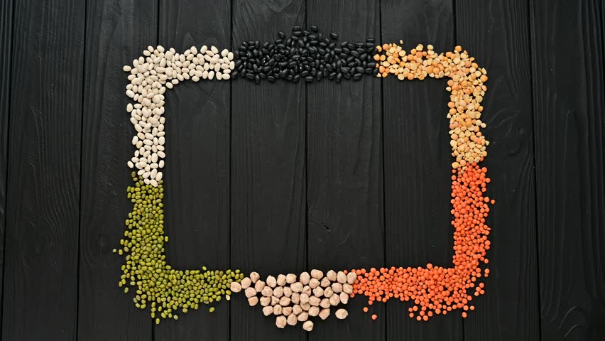 Variety of legumes on a black wooden background in the form of a frame.