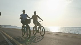 Caucasian couple taking pleasure in the ride on beach cruiser bikes, pedaling on a wonderful route near the sea, handheld shot. - Powered by Shutterstock - Get 15% off with code: PIKWIZARD15