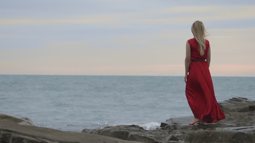 back view of sad woman wearing a red dress by the sea thinking