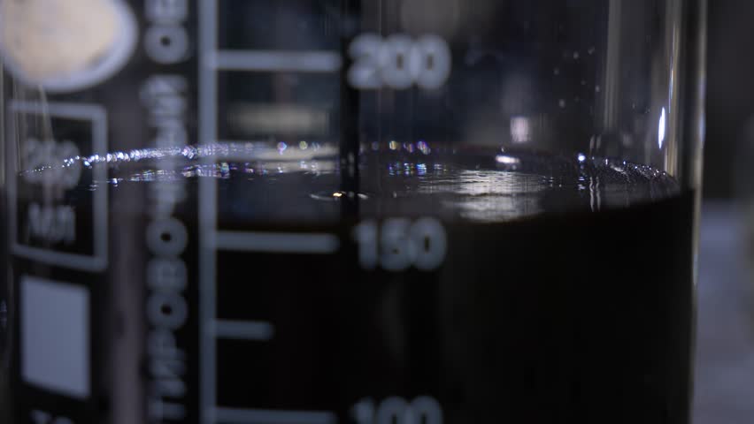 scientist pours clean oil black liquid into flask and test tubes for purification