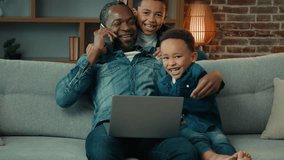 Adult African American father with laptop working at home distant job talking mobile phone sit on couch at living room little child son hug embrace daddy man from back children kids boys hugging dad - Powered by Shutterstock - Get 15% off with code: PIKWIZARD15