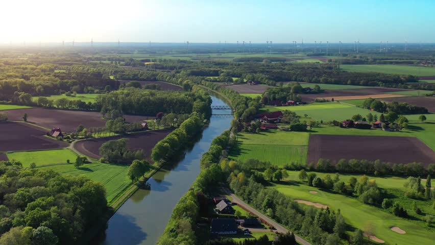 Summer aerial drone view landscape navigable river with bridges, agricultural fields and forests and farmers houses in Germany countryside. Cargo ship on the river. High quality 4k footage Royalty-Free Stock Footage #1100458873