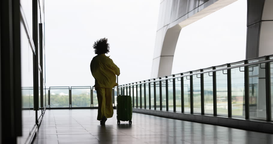 Back of woman traveler who rejoices at opening of borders after covid-19 epidemic. Adventurous woman can finally travel world calmly and freely. Woman dances while hopping through airport with luggage Royalty-Free Stock Footage #1100460731