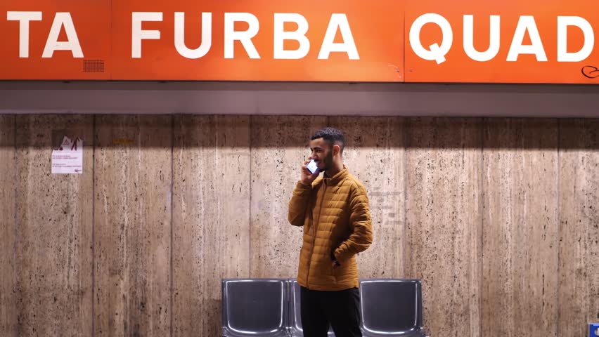 young confident african man talks on phone while waiting for subway