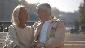 Happy senior husband and wife hugging together on bench outdoors. Healthy elderly retirement couple relax and enjoy romantic outdoor vacation together. Realtime - Powered by Shutterstock - Get 15% off with code: PIKWIZARD15