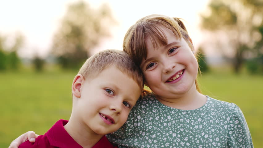 Sister brother smiling while looking camera sunset. friendship portrait boy girl. first graders kid sunset. childish smile. childhood dream child. teamwork. friends hugging camera. happy family sunset | Shutterstock HD Video #1100465853