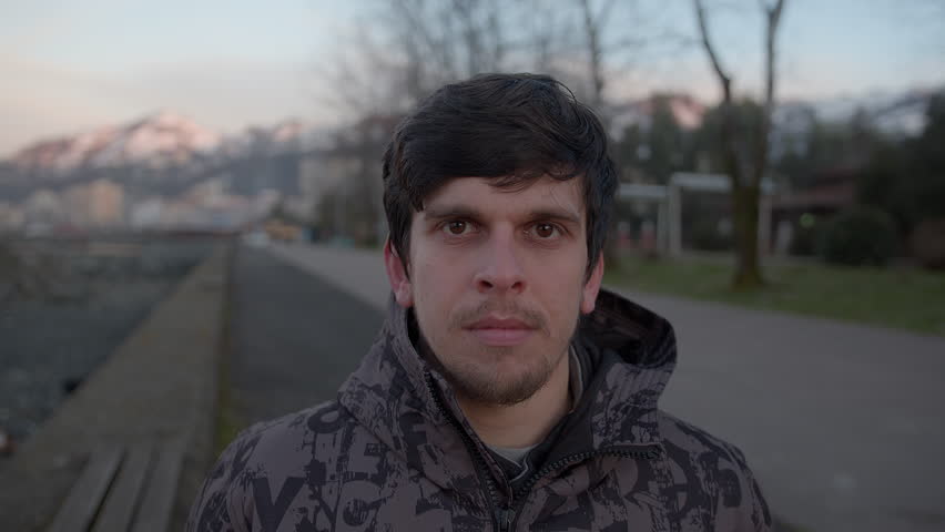 Handsome young man in a coat conducting a point of view video conference call outdoors