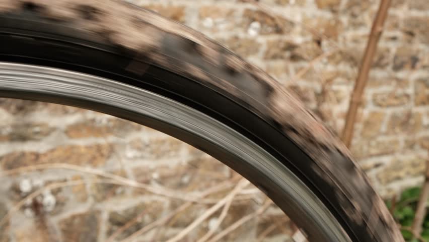 An old dirty bicycle wheel is spinning. Close-up.