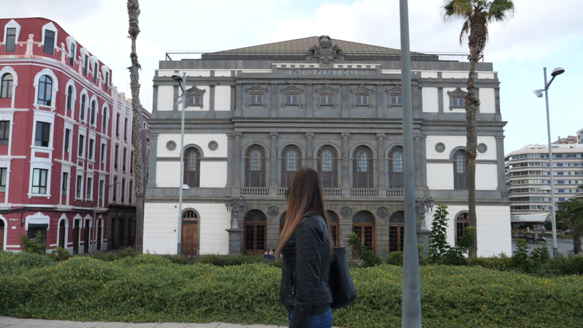 woman walks admiring the Benito Perez Galdos theater in Las Palmas de Gran Canaria and on a sunny day.