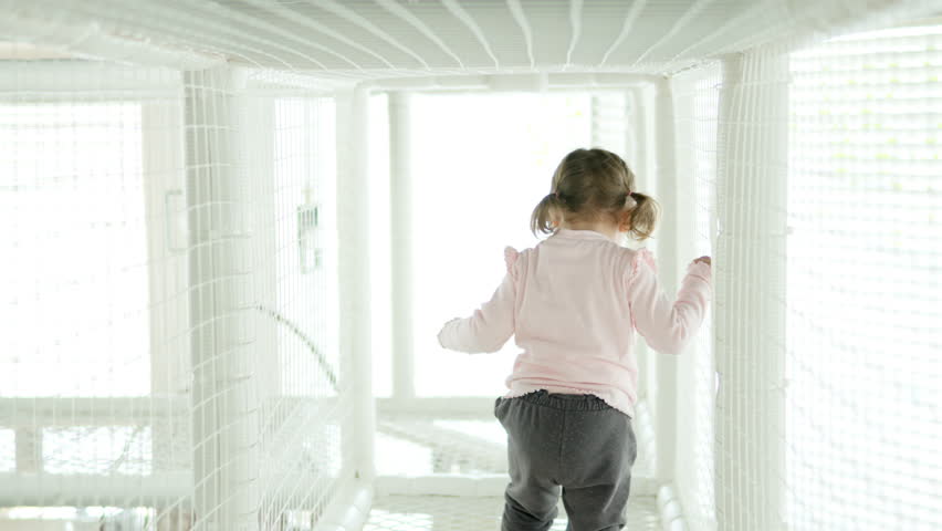 3 Year Old Toddler Girl Cautiously Walking Inside the Rope Maze for Children in slow motion, rear view
