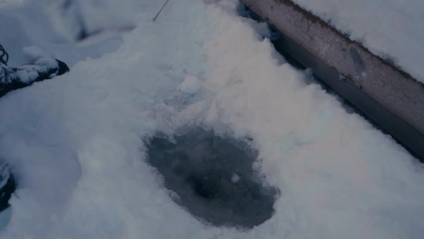 Man Is Holding An Axe Making A Hole In A Frozen Lake. High Angle