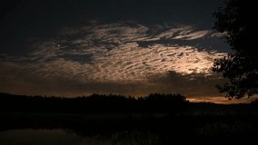 Time lapse of full moon lit night clouds and an airplane flying by in dark starry sky making shooting star effect. Filmed at shore line of a misty lake, planet Jupiter brightest object in the sky. - Powered by Shutterstock - Get 15% off with code: PIKWIZARD15