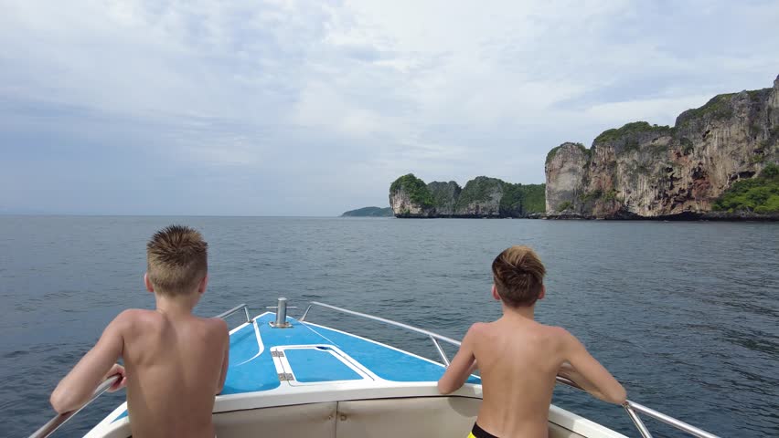 A couple of boys are watching the Phi Phi Islands, two boys are traveling on a speedboat around the islands in Thailand | Shutterstock HD Video #1100474827