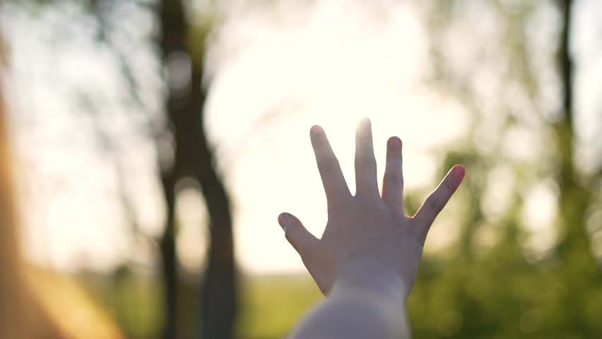 Happy girl stretches her hands to sun. Children palm in rays of sun at sunset.Young woman raising her hands praying at sunset or sunrise.Freedom in nature and spirituality concept.Fingertips touch sun Royalty-Free Stock Footage #1100477593