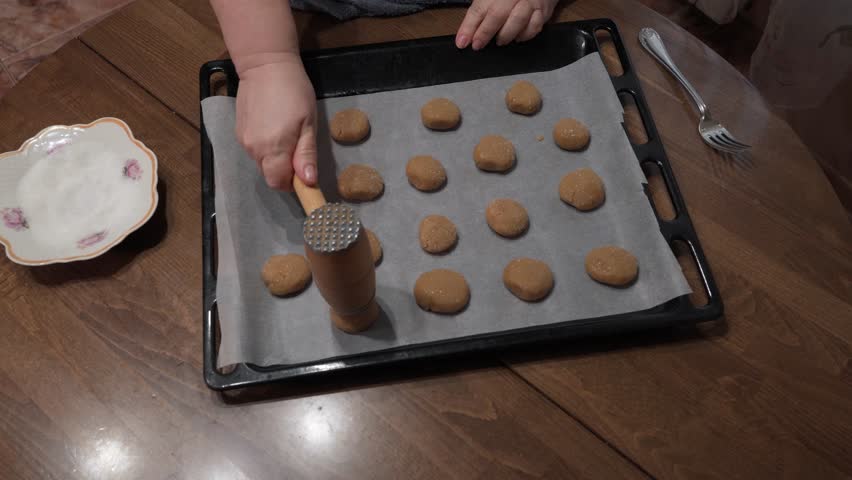 A woman makes a homemade cookie, she makes a pattern on the surface of the dough..