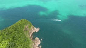 Aerial video of a sports boat sailing fast alongside an island full of trees. Kopan Gan Thailand