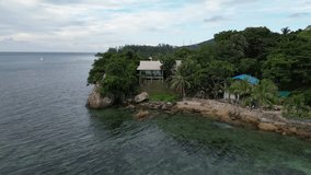Aerial video of a small cabin around coconut trees and sea of Koh Phangan Thalind.