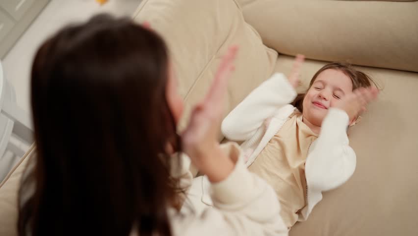 Mother and daughter spending time at home, playing peekaboo