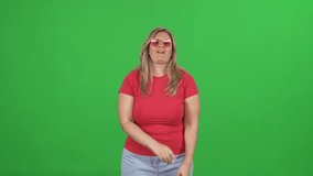 Caucasian woman dances to the music on a green background, cheerful woman dancing and having fun, chroma key template, plus size model.