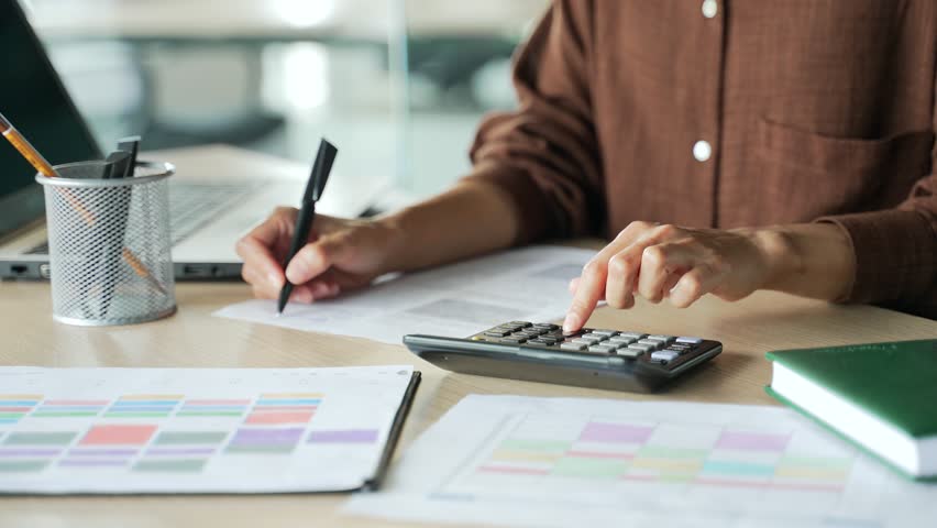 Close up hands of accountant clerk work with papers at desk in modern glass office Concentrated bookkeeper count financial report on calculator with documents and laptop computer at workplace indoors Royalty-Free Stock Footage #1100486265