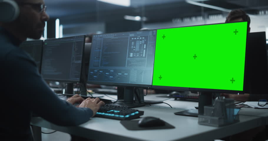 Close Up of a Software Developer Working on a Desktop Computer with Green Screen Mock Up Display. Specialist Typing on Keyboard, Coding and Implementing a New Technical Feature, Working in an Agency Royalty-Free Stock Footage #1100488293