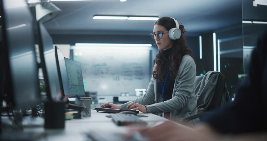Portrait of a Thoughtful Young Engineer Working on Computer in a Technological Office Environment. Beautiful Multiethnic Woman Wearing Headphones, Writing Software Code for a Blockchain Project | Shutterstock HD Video #1100488307