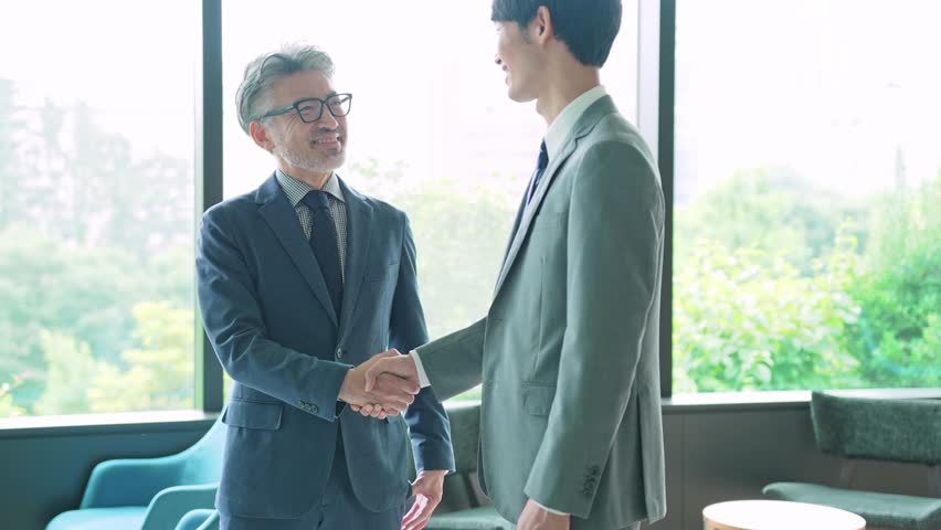 Middle aged executive man and young businessperson shaking hands in the office. Royalty-Free Stock Footage #1100493409