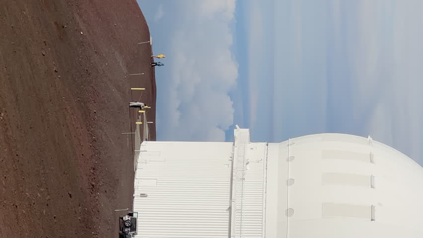 Vertical oriented for mobile content of astronomic telescopes on Mauna Kea summit at sunset on Big Island, Hawaii USA. Top of mountain with international science Observatories at red volcanic crater