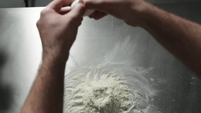 Man hands add egg to flour, slow motion. Egg falling into heap of flour. A young male chef puts egg yolks into the pile of flour for making pastry or bread dough.