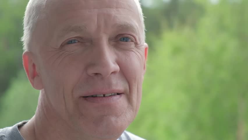 a man sneezes, a senior man covers his face with his hands, an allegory to pollen, man on the street, a balcony, fresh air