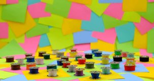 metal spools with Multicolored thread for sewing machine on a rotating table with multicolored paper sticky notes on background