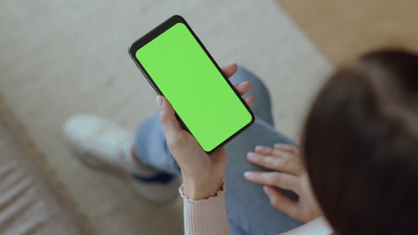 Online order. Top view of unrecognizable woman holding smartphone with green chroma key screen, studying assortment on mobile app, choosing product, empty space | Shutterstock HD Video #1100508337