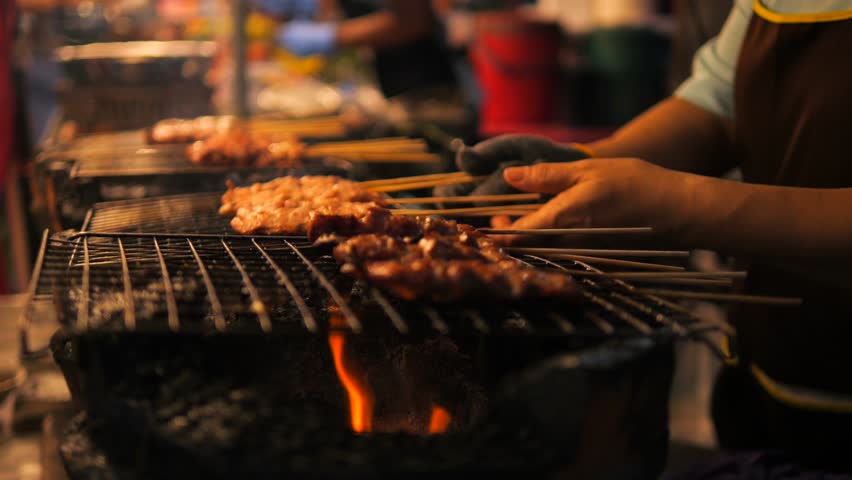 Local Asian Street Food. Chef Cooking Chicken Satay on Fire Bbq Grill at Night Market in Phuket Old Town. High Quality Cinematic 4K Slowmotion Thai Cuisine Footage. Thailand.