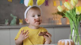 Little cute boy wearing bunny ears eating chocolate easter bunny while sitting at table at home. - Powered by Shutterstock - Get 15% off with code: PIKWIZARD15
