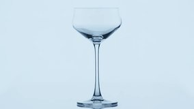 Clear water pouring into a standing wine glass in light gray background. Water is flowing smoothly into the empty wine glass. High quality 4k footage