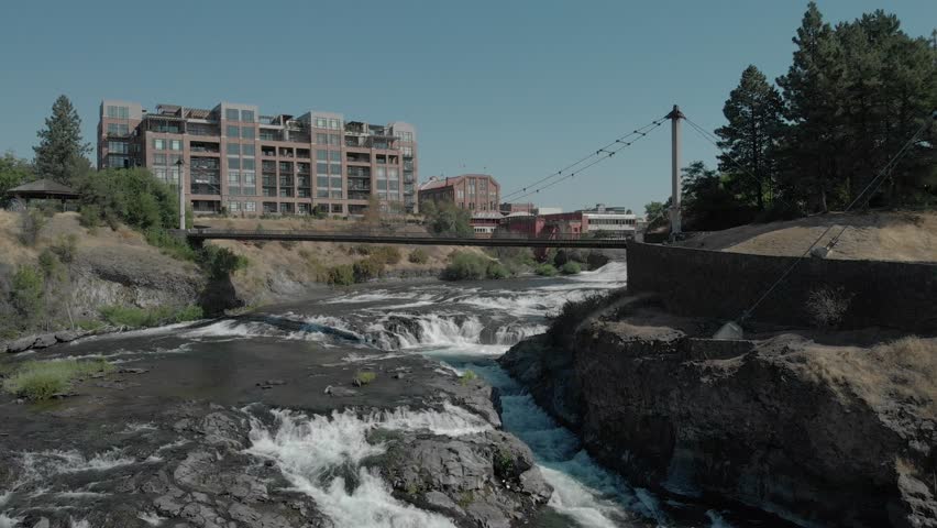 Drone shot of a bridge in downtown Spokane over the Spokane river, late afternoon, buildings in the backround