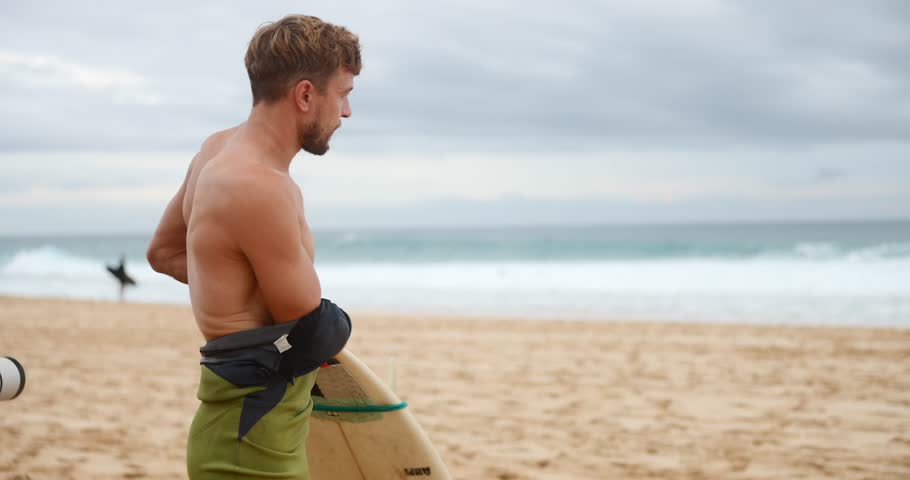 Professional surfer wearing a wetsuit on banzai pipeline north shore Oahu Hawaii. preparing to surf on a beach. Royalty-Free Stock Footage #1100518769