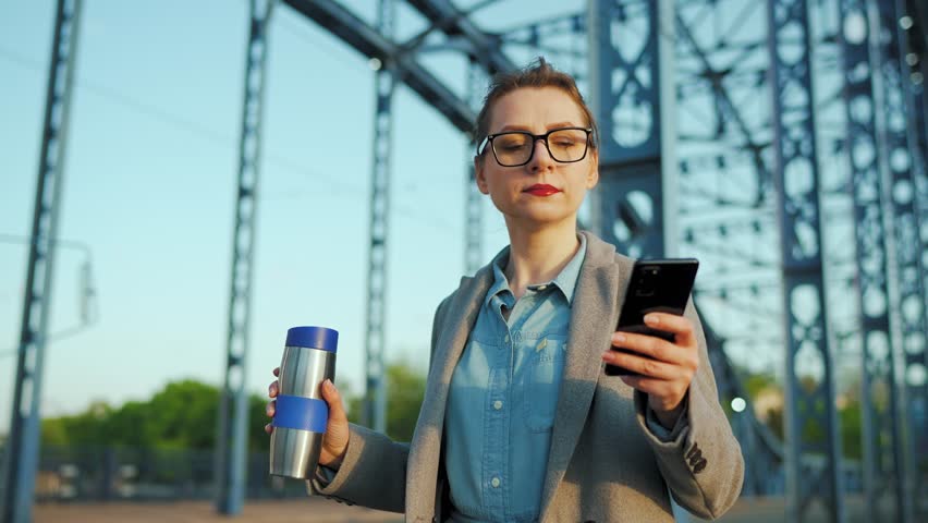 Woman in a coat, walking around the city in the early morning, drinking coffee